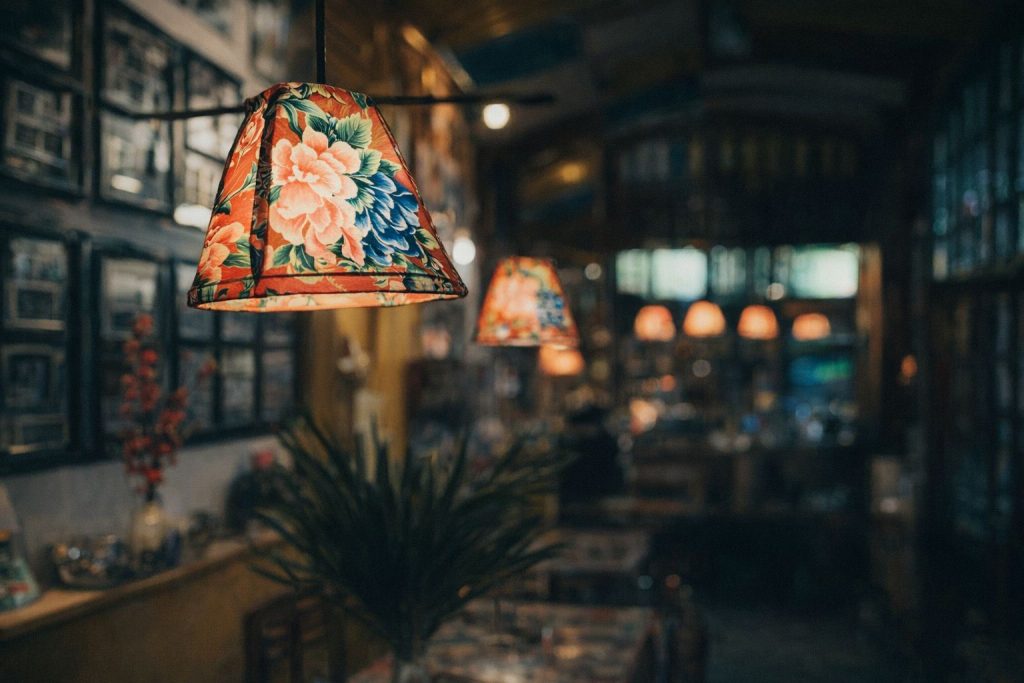 Sfeervolle café-verlichting met kleurrijke bloemenpatronen op lampenkappen.