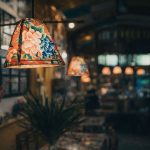 Sfeervolle café-verlichting met kleurrijke bloemenpatronen op lampenkappen.